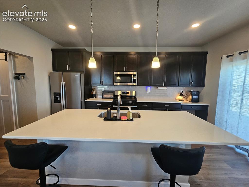 Image 13 of 35: Spacious kitchen island with a built-in sink, dark wood-finish cabinetry, s