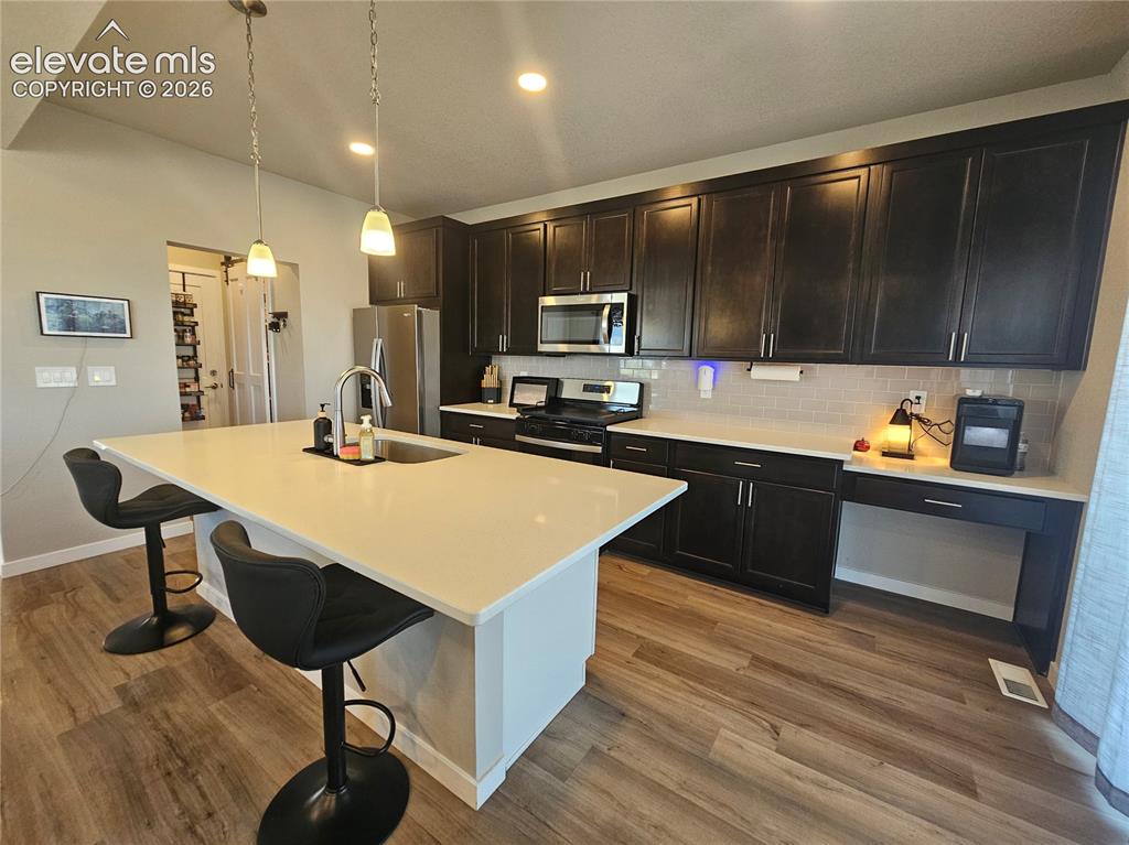Image 14 of 35: Kitchen featuring wood-finish flooring, dark wood cabinetry, light countert