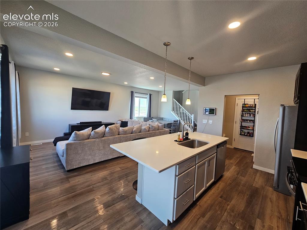Image 15 of 35: Open-concept living area with wood-finish flooring, recessed lighting, and
