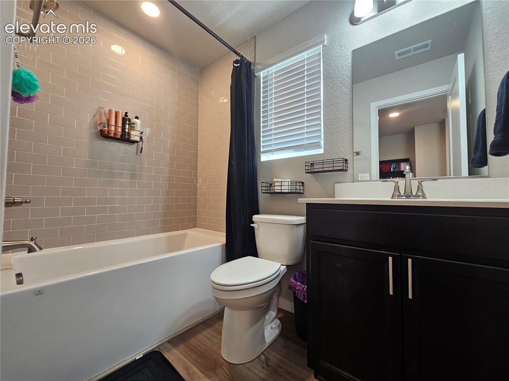 Image 23 of 35: Bathroom featuring a shower-tub combination with subway tile surround, dark