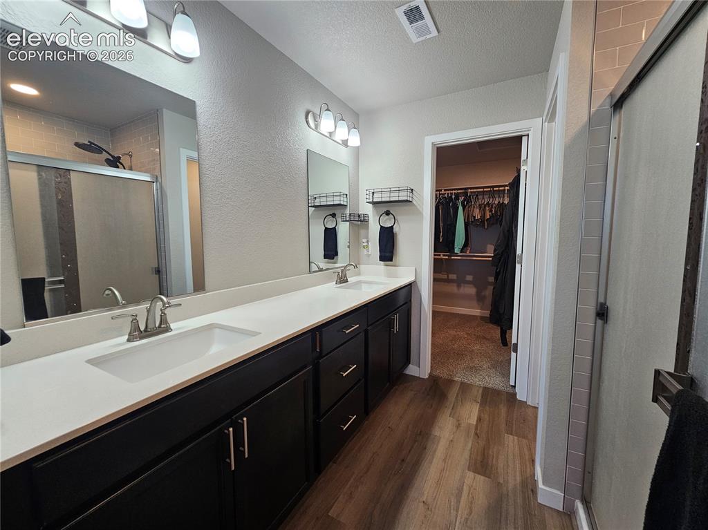 Image 28 of 35: Dual vanity with white countertops, dark wood-finish cabinetry, and brushed