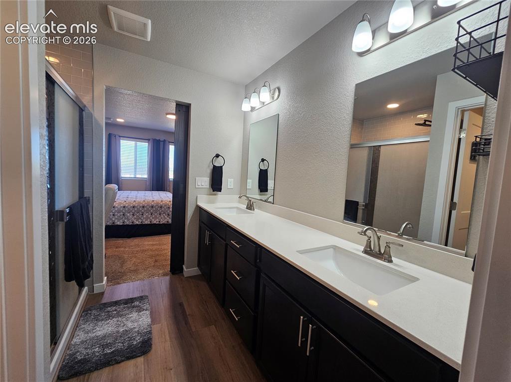 Image 30 of 35: Dual vanity with dark wood-finish cabinetry and light-colored countertops