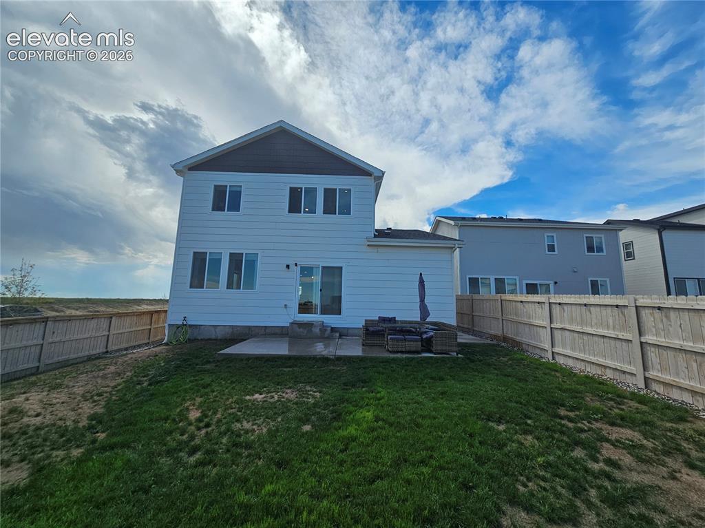Image 32 of 35: Private fenced backyard with a concrete patio, white siding, and a gabled r