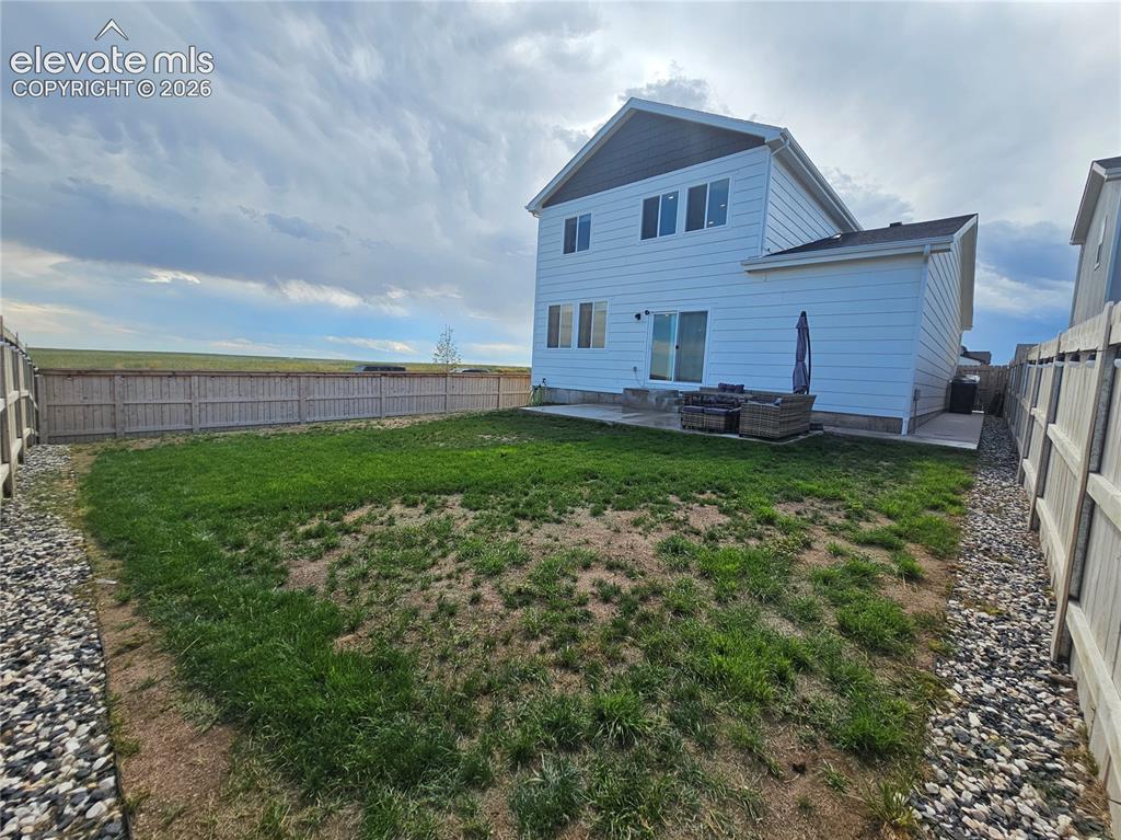 Image 33 of 35: Spacious backyard featuring a sloped lawn area, full privacy fencing, and a