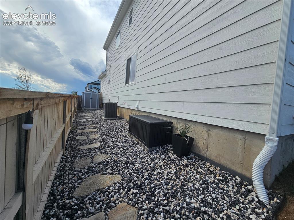 Image 35 of 35: Exterior siding with foundation, rock ground cover, and stepping stones