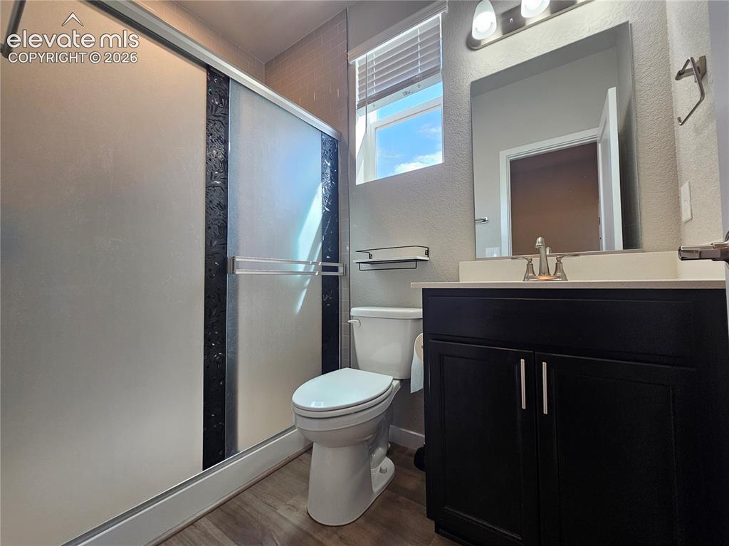 Image 5 of 35: Frosted glass shower enclosure, dark wood-finish vanity with white countert