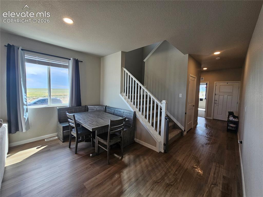 Image 8 of 35: Expansive wood-finish flooring, staircase with white newel posts, recessed