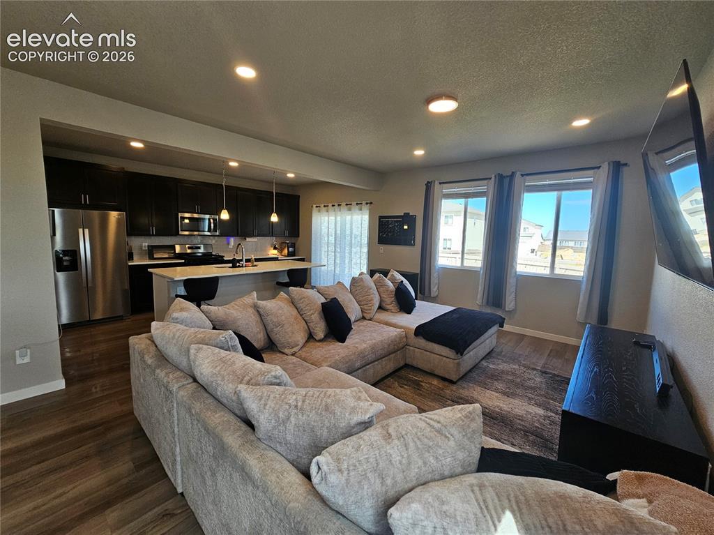 Image 9 of 35: Open-concept kitchen and living area featuring wood-finish flooring, recess