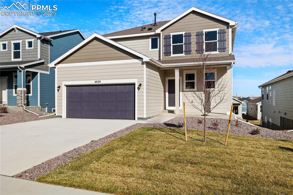 Caption: View of front of home with covered porch, driveway, a front yard, and an attached garage