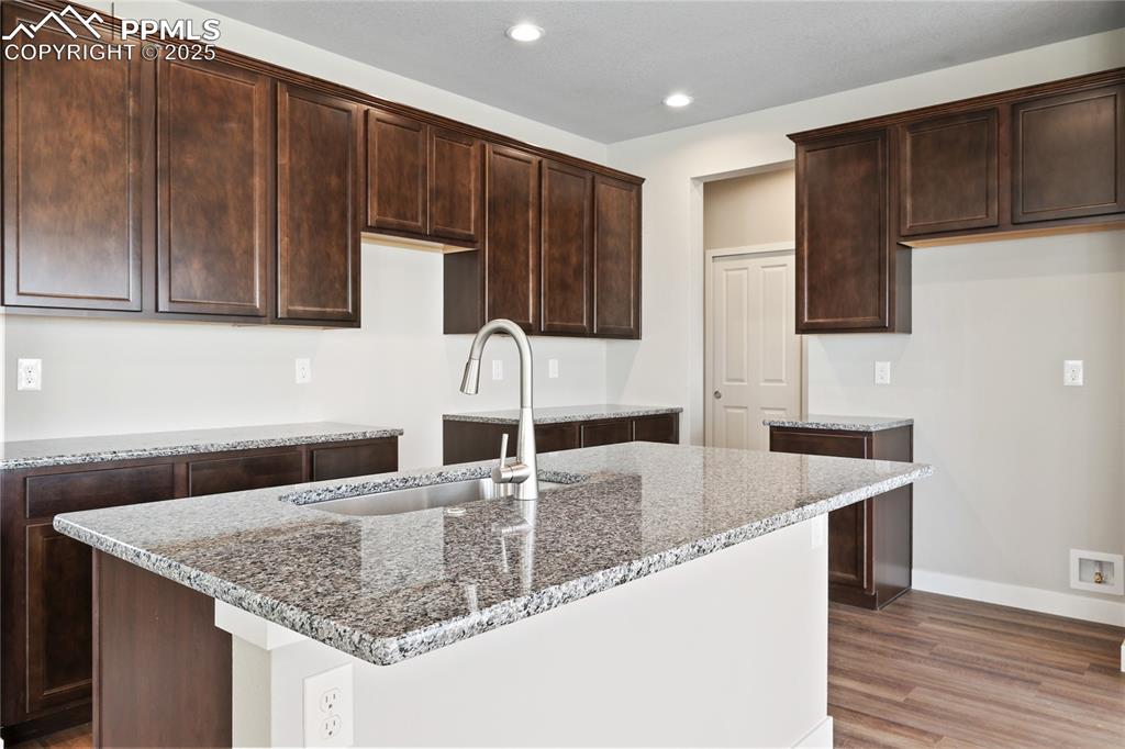 Image 11 of 25: Kitchen featuring a kitchen island with sink, recessed lighting, and dark b