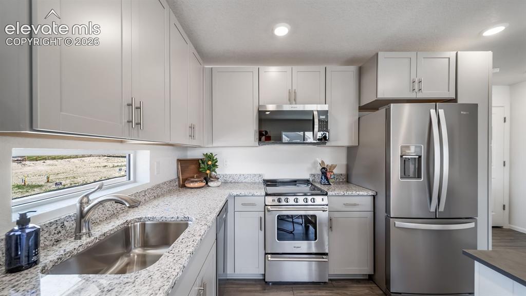 Image 13 of 26: Modern kitchen featuring light gray cabinetry, stainless steel appliances, 