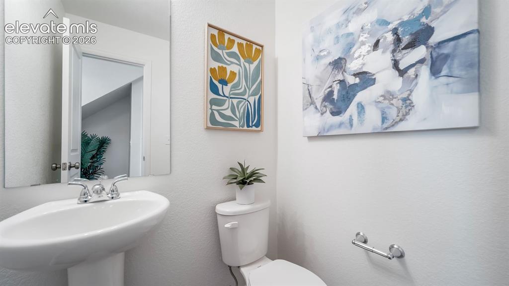 Image 19 of 26: Pedestal sink with chrome faucet, white toilet, and minimalist wall mirror
