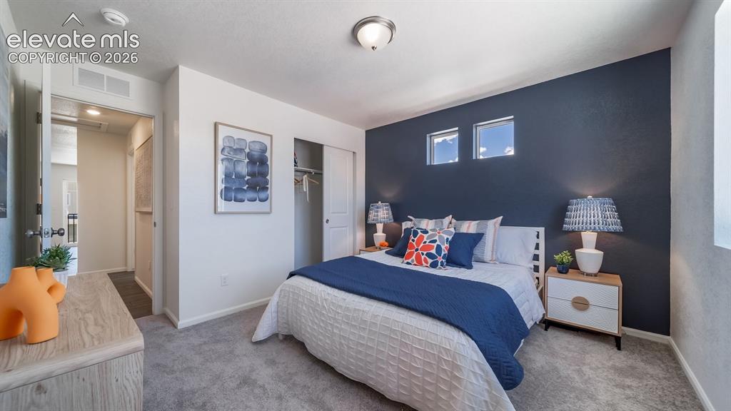 Image 21 of 26: Spacious bedroom featuring plush gray carpeting, a dark accent wall with tw