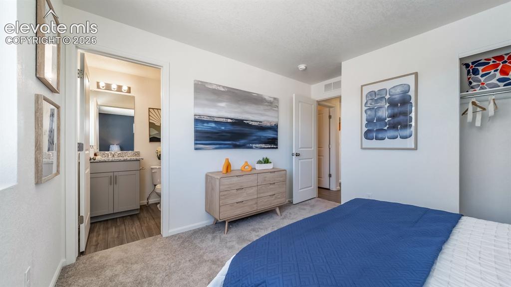 Image 22 of 26: Carpeted bedroom featuring white walls, an open closet, and a doorway to a 