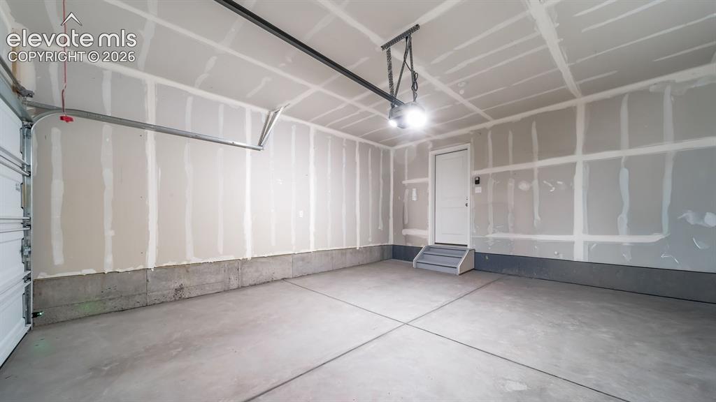 Image 24 of 26: Spacious garage featuring a concrete floor, overhead lighting, and an inter