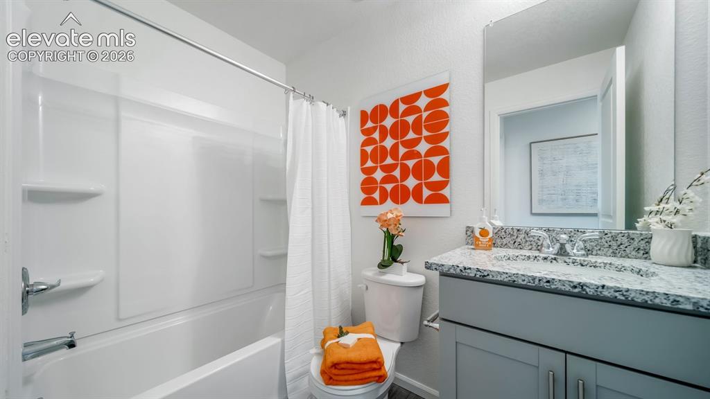 Image 5 of 26: Bathroom featuring a white tub with integrated shelving, a gray vanity with