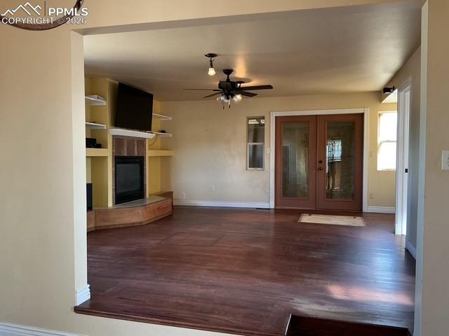 Image 17 of 36: Unfurnished living room with a tiled fireplace, dark wood-style flooring, a