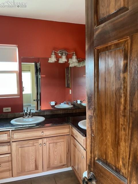 Image 31 of 36: Bathroom with double vanity and dark tile patterned flooring