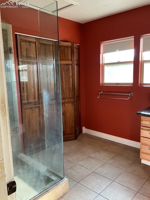 Image 32 of 36: Bathroom with vanity, light tile patterned flooring, and a stall shower