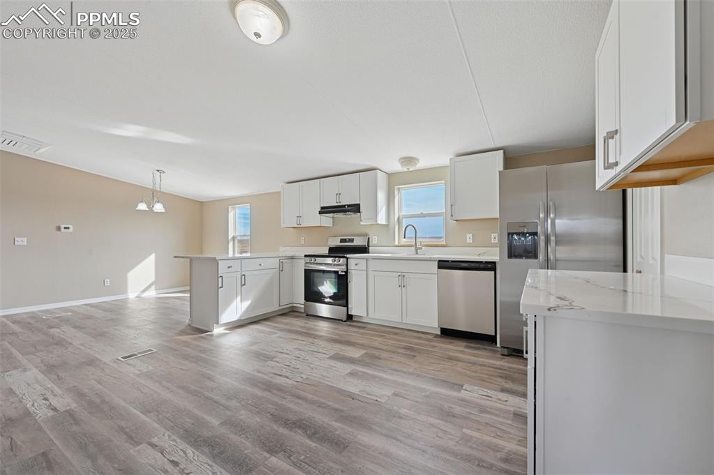 Image 10 of 33: Kitchen with appliances with stainless steel finishes, white cabinetry, a p