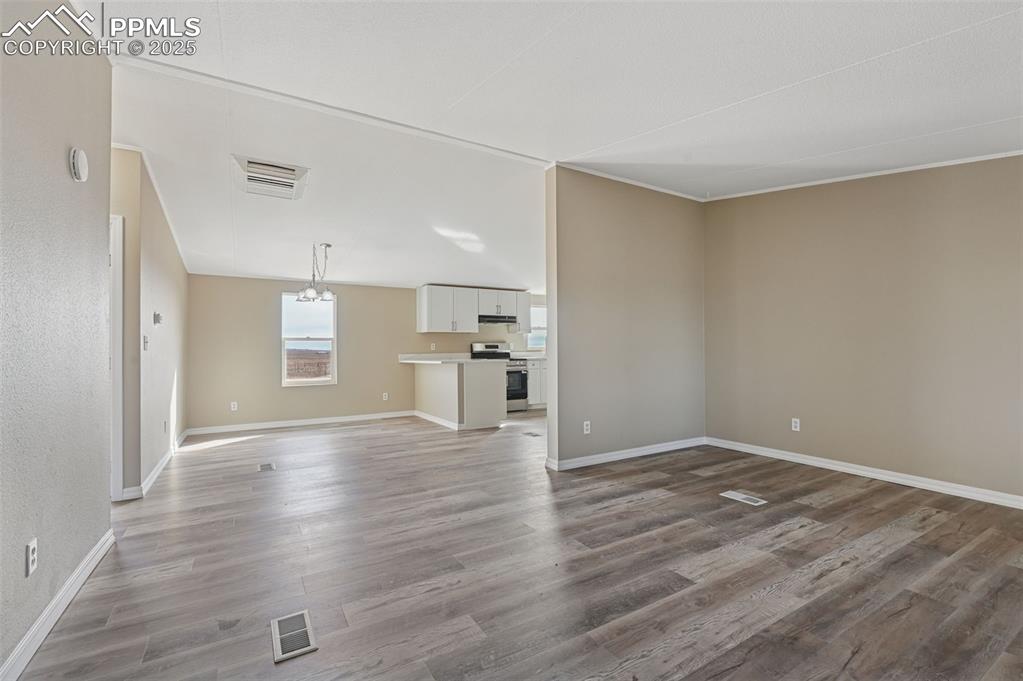 Image 12 of 33: Unfurnished living room with dark wood-style flooring and a chandelier