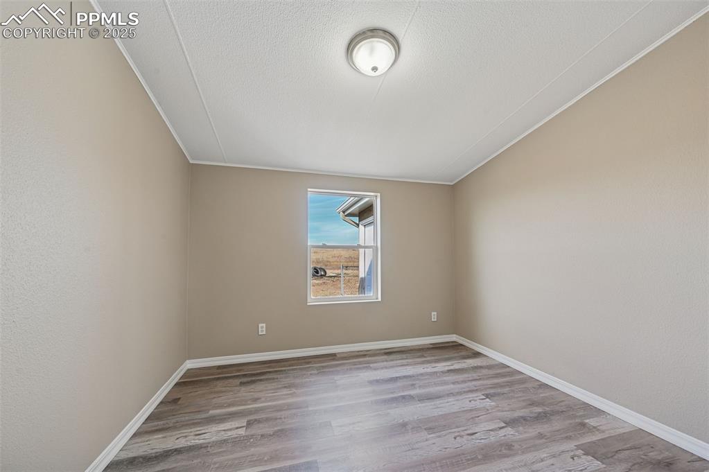Image 17 of 33: Spare room with light wood-type flooring and a textured ceiling