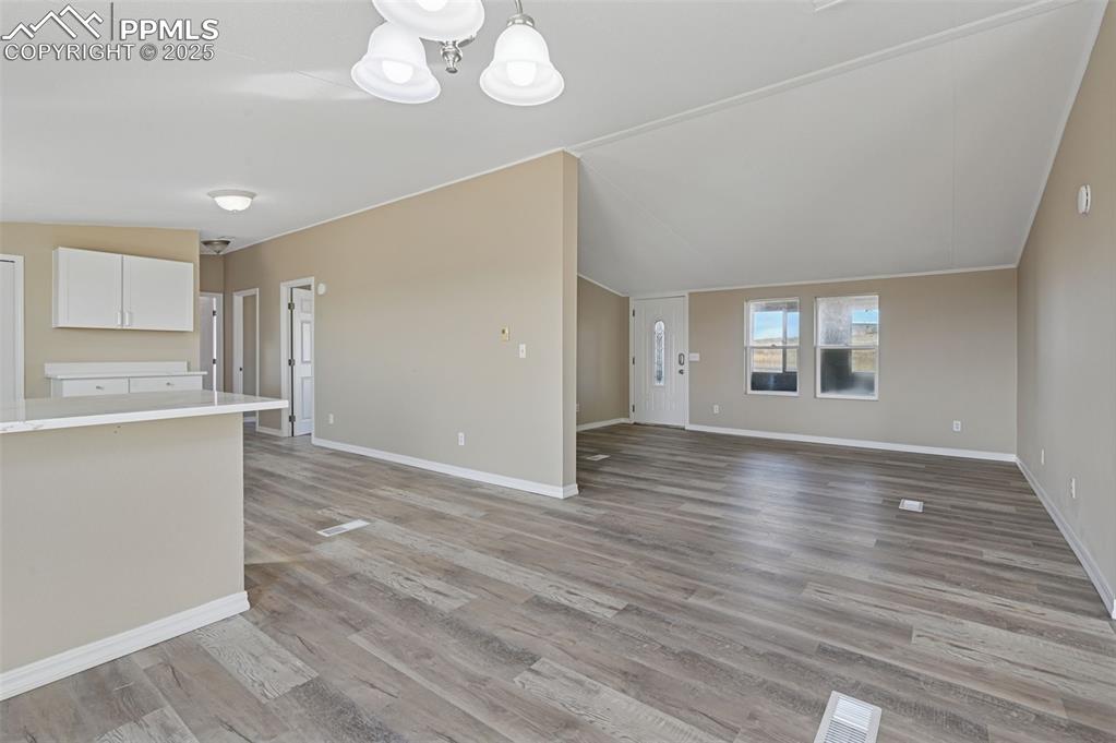 Image 18 of 33: Unfurnished living room featuring lofted ceiling, light wood-style floors,