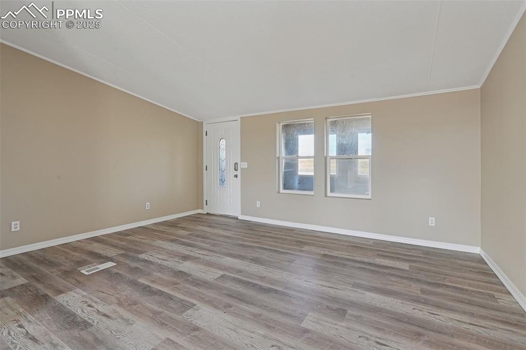 Image 19 of 33: Spare room with wood finished floors and crown molding