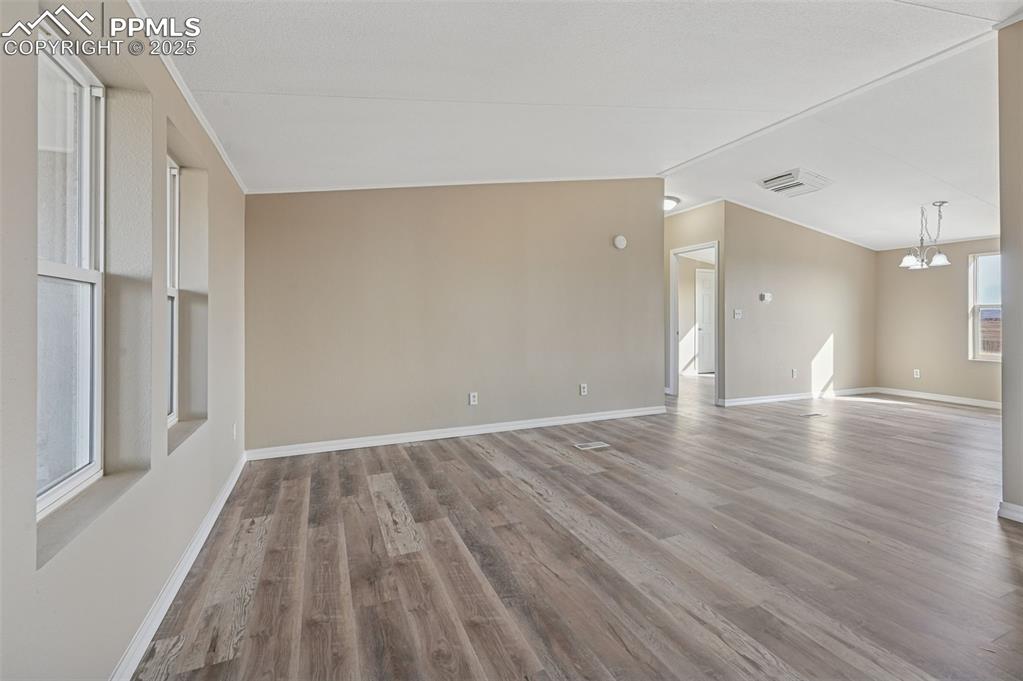 Image 20 of 33: Spare room with light wood-type flooring and a chandelier