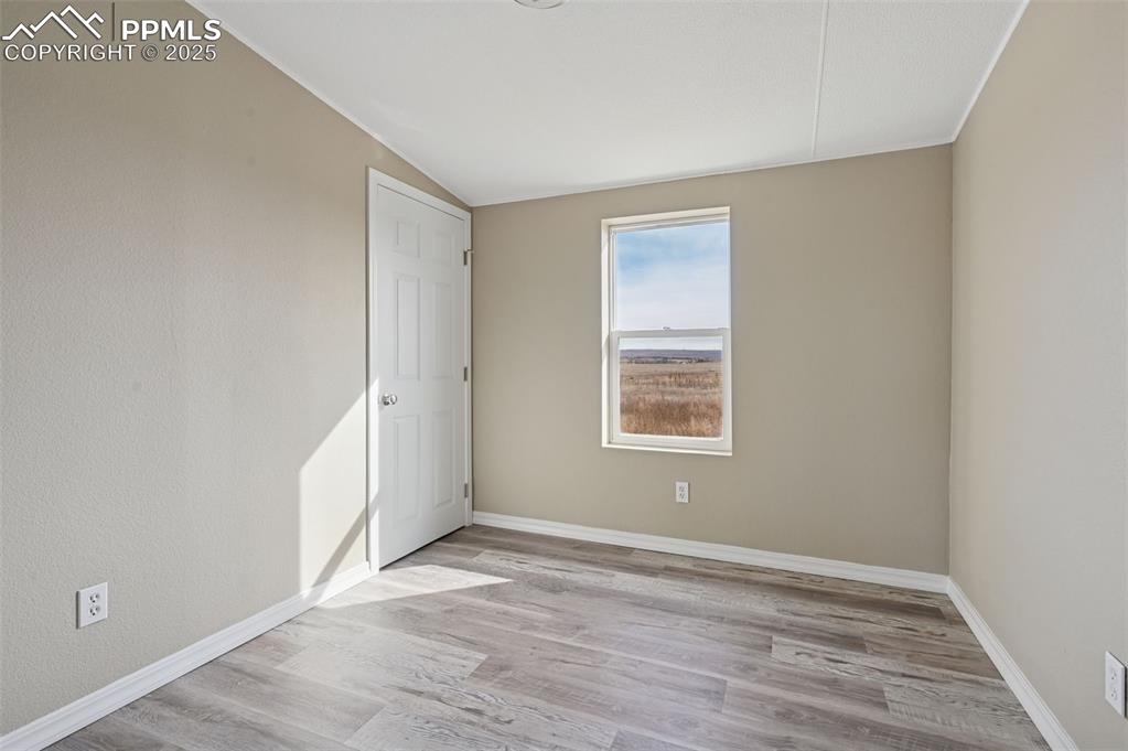 Image 21 of 33: Empty room featuring light wood-style flooring and lofted ceiling