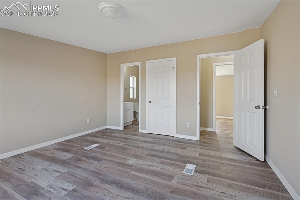 Image 24 of 33: Unfurnished bedroom featuring light wood-type flooring and connected bathro