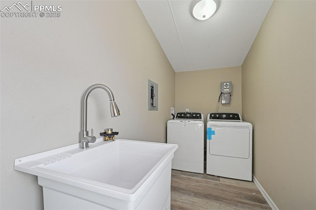 Image 27 of 33: Laundry area with wood finished floors, washer and dryer, and electric pane
