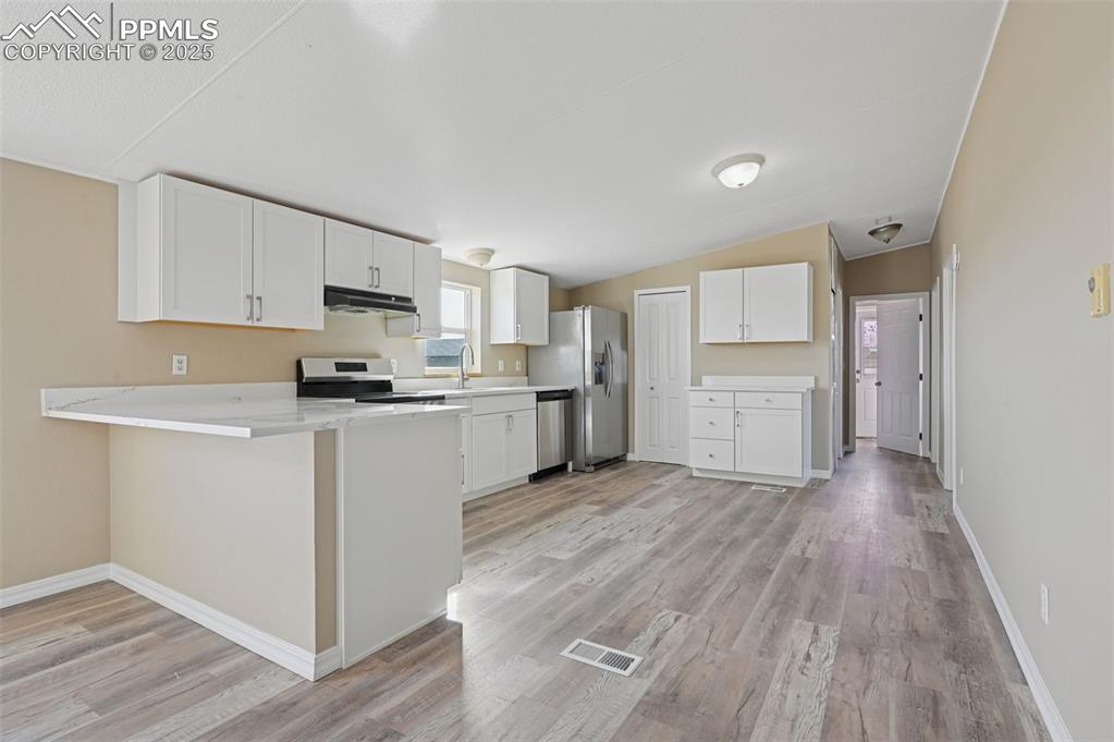 Image 9 of 33: Kitchen with white cabinets, appliances with stainless steel finishes, ligh