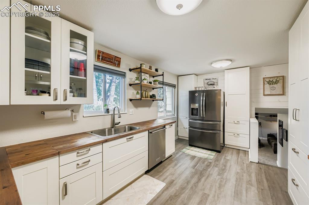Image 10 of 27: Kitchen with white cabinets, stainless steel appliances, wooden counters, o