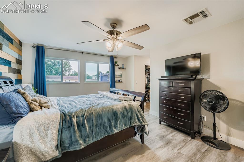 Image 14 of 27: Bedroom with wood finished floors, a walk in closet, and a ceiling fan