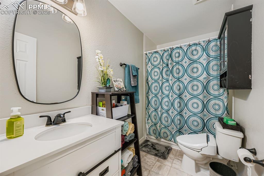 Image 15 of 27: Bathroom featuring vanity, a textured wall, and a shower with curtain