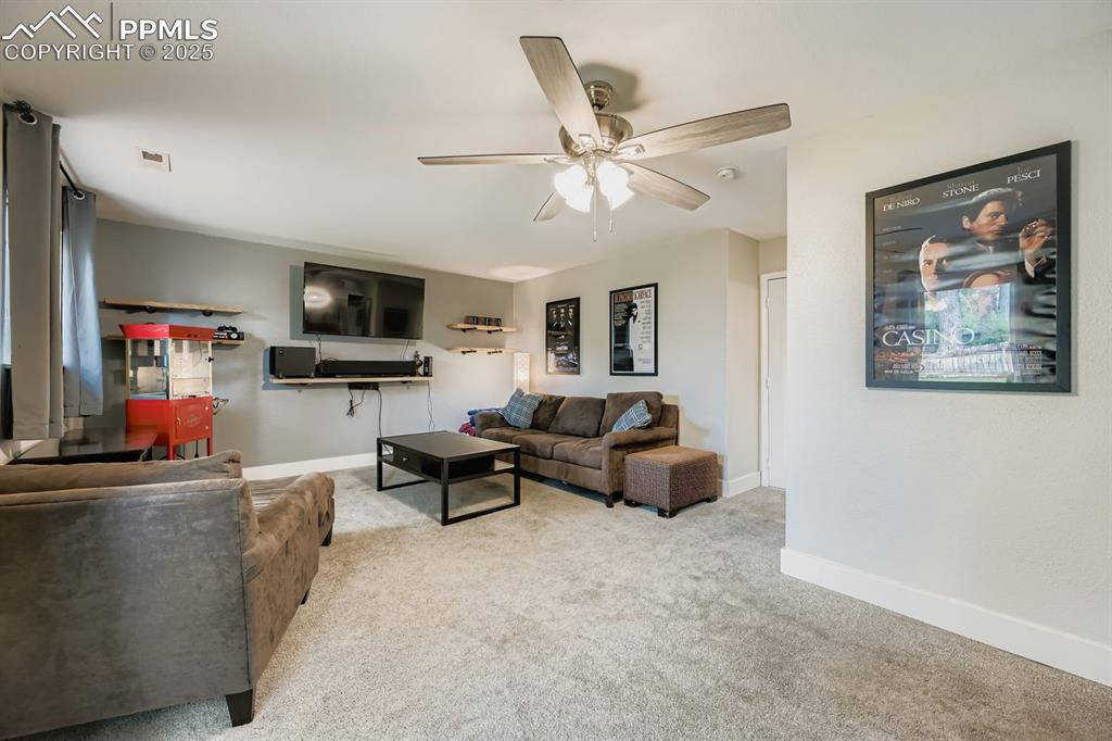Image 23 of 27: Carpeted living room featuring ceiling fan and baseboards
