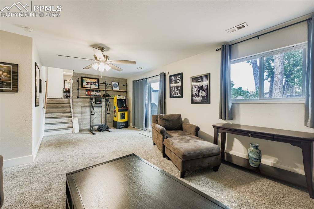 Image 24 of 27: Living room with carpet floors, stairway, and ceiling fan