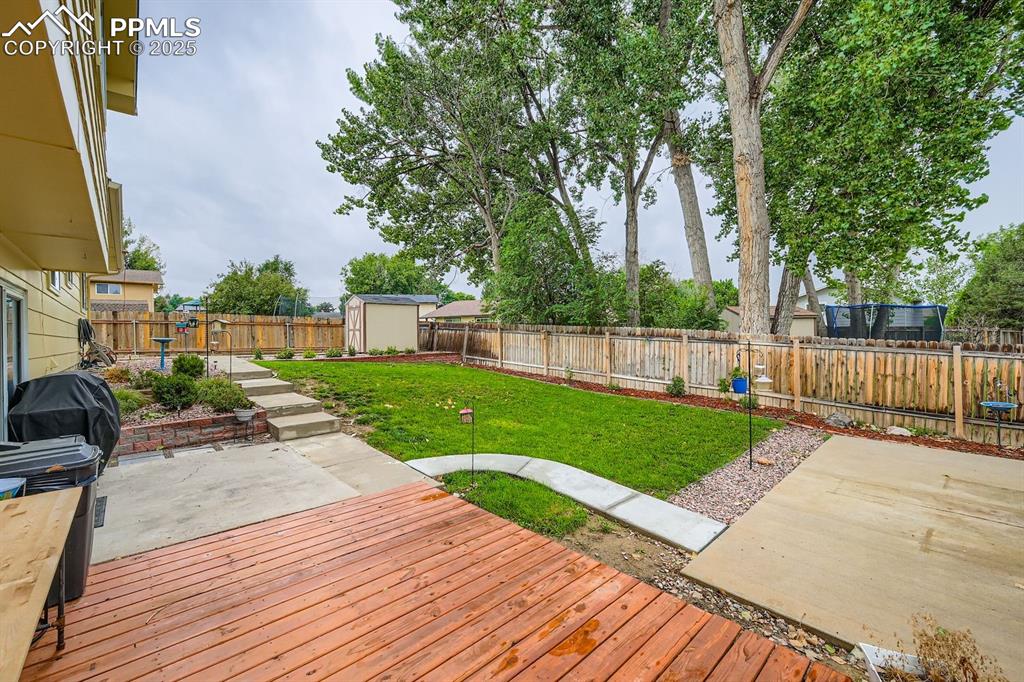 Image 25 of 27: Wooden deck with a fenced backyard, a shed, a grill, and a patio
