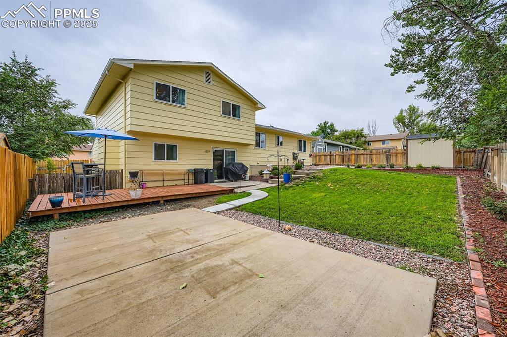 Image 26 of 27: Rear view of house featuring a fenced backyard, a deck, and a patio area