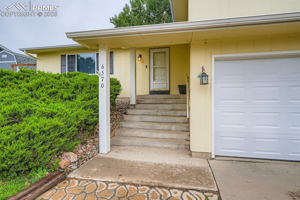 Image 3 of 27: Property entrance featuring a garage and a porch
