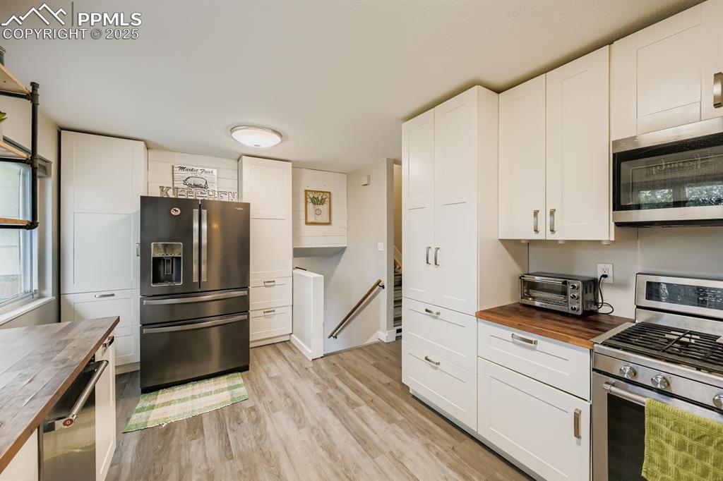 Image 9 of 27: Kitchen with butcher block countertops, stainless steel appliances, white c