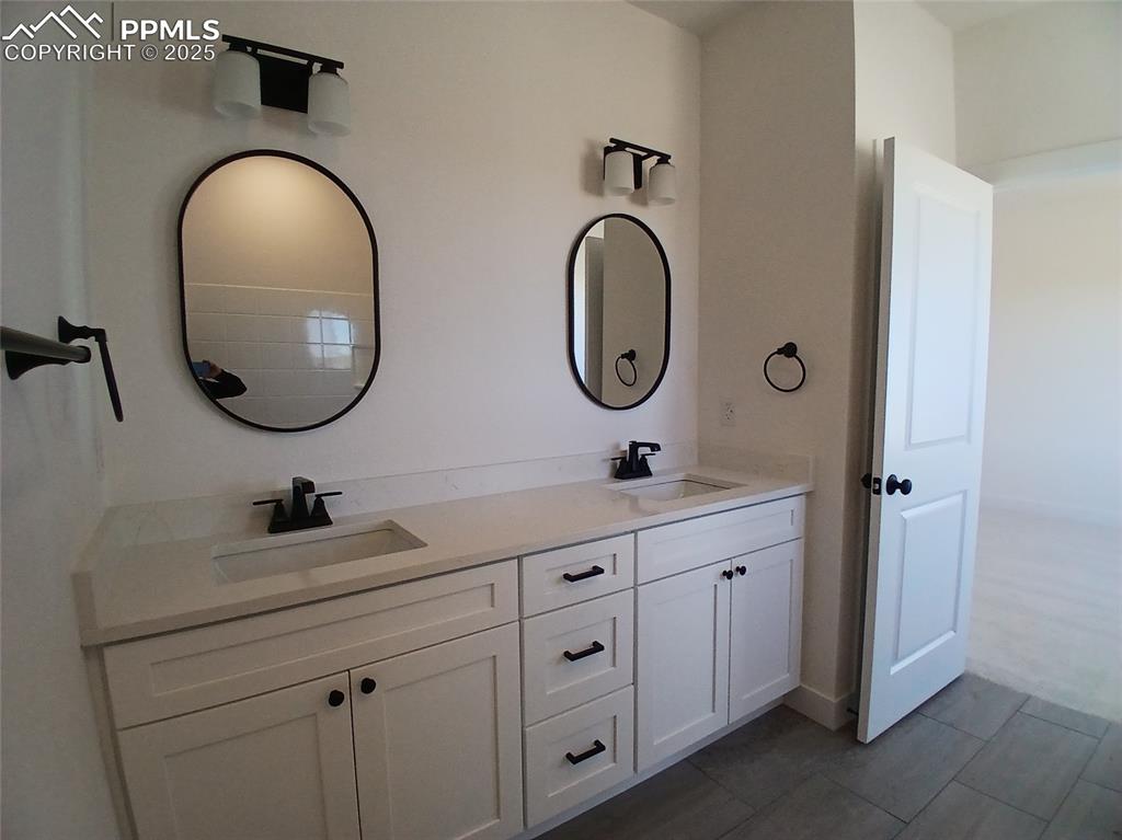 Image 24 of 39: Double sinks, quartz countertop & tile floor. 