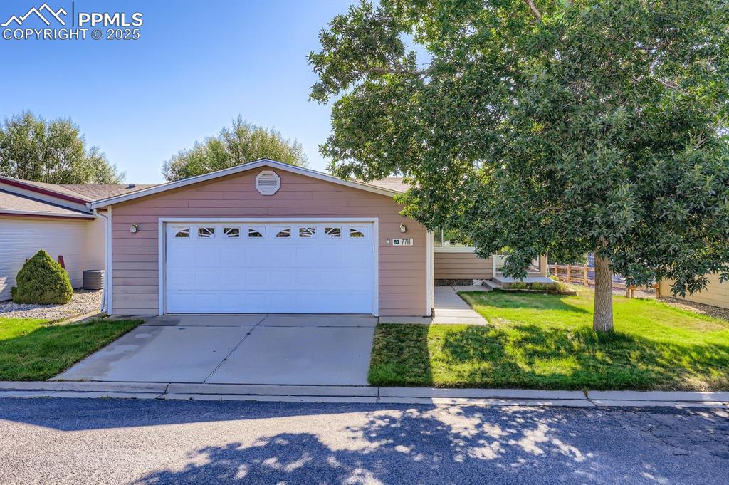 Caption: View of front of home featuring concrete driveway, a front lawn, and a garage