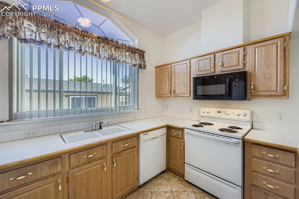 Image 10 of 29: Kitchen featuring white appliances, light countertops, and light tile patte
