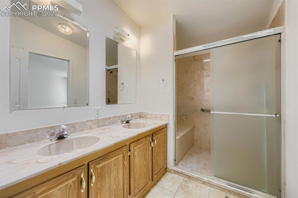 Image 19 of 29: Full bath featuring a stall shower, double vanity, and light tile patterned
