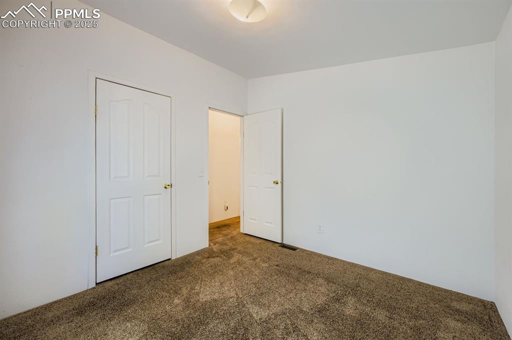 Image 24 of 29: Unfurnished bedroom with dark colored carpet