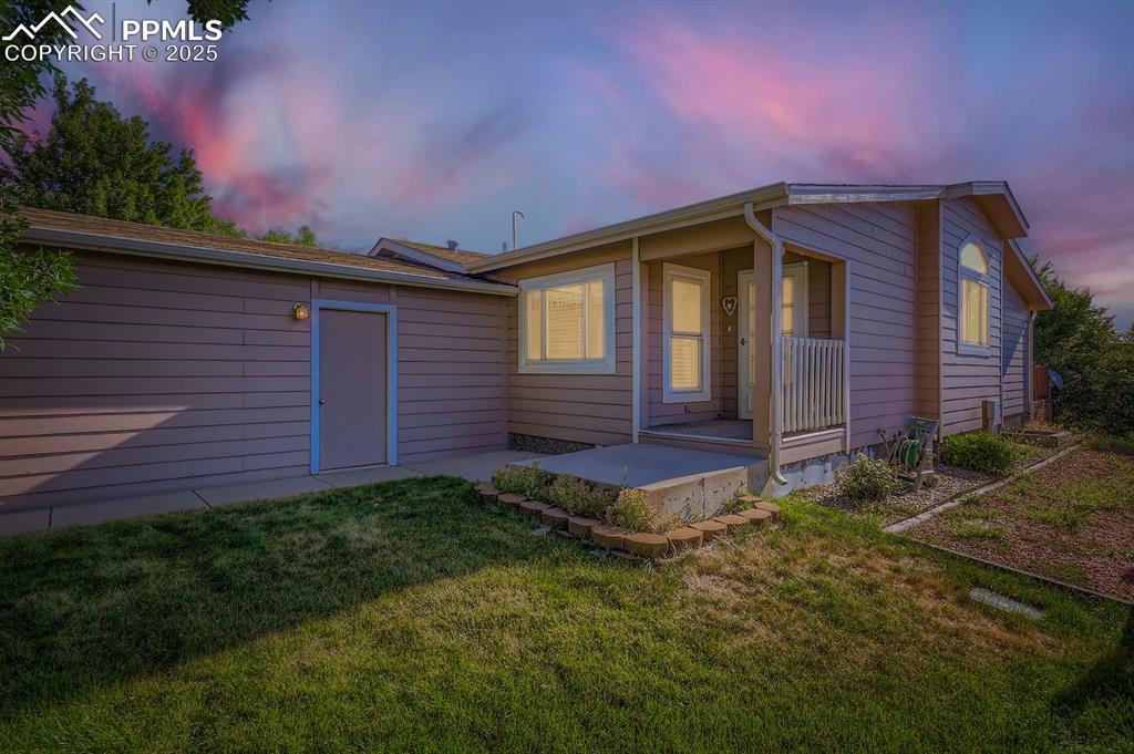 Image 3 of 29: Back of house at dusk featuring a yard and a porch