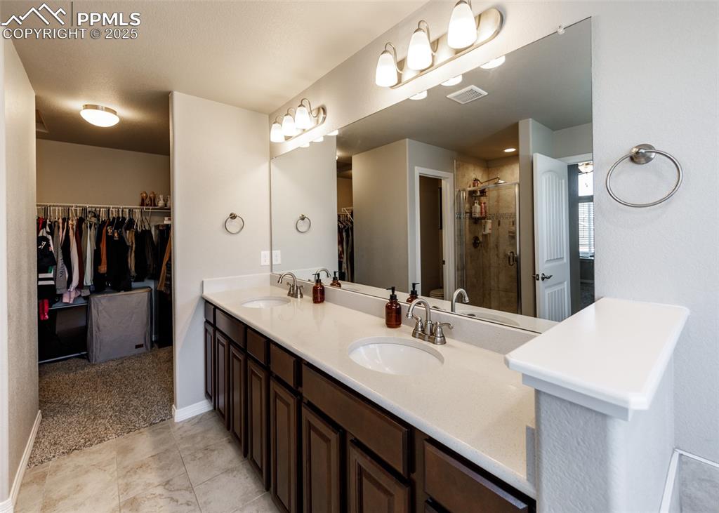 Image 22 of 43: Another view of the primary bathroom with double vanity and into walk in cl