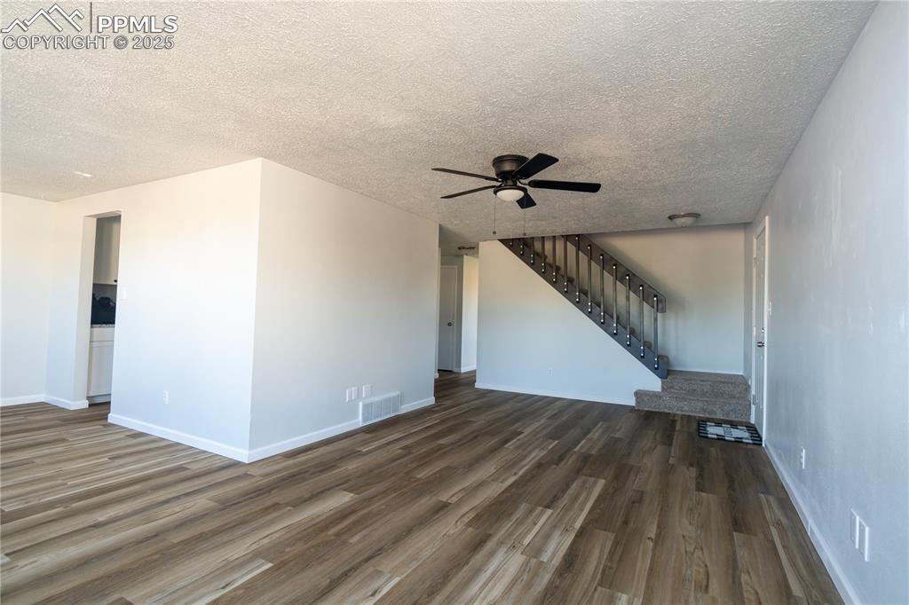 Image 10 of 37: Unfurnished living room featuring stairs, dark wood finished floors, a ceil